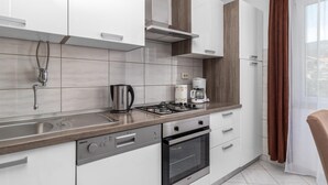A modern kitchen with a gas stove, oven, sink, and a coffee maker. - 3 bedroom beach front apartment in Jadranovo (Jadranovo)
