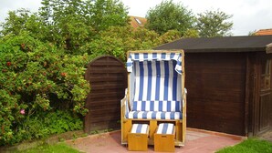 Una terraza de madera con una silla de playa azul y blanca a rayas y un taburete a juego.