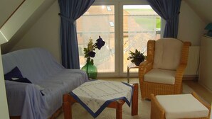 Un dormitorio con cama, una silla, una mesita y vistas al exterior.