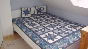Una habitación pequeña con cama individual, techo inclinado y tragaluz.