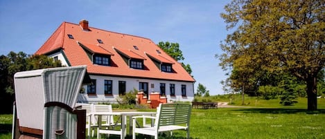 A house with a red roof, white walls, and a garden with a table and chairs.