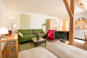 A living room with a green sofa, a red armchair, a television, and a wooden table. - Striker - Manor Ketelshagen - romantic, quiet location (Putbus)