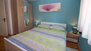 Een slaapkamer met een bed, nachtkastjes, een kledingkast en een schilderij aan de muur.
