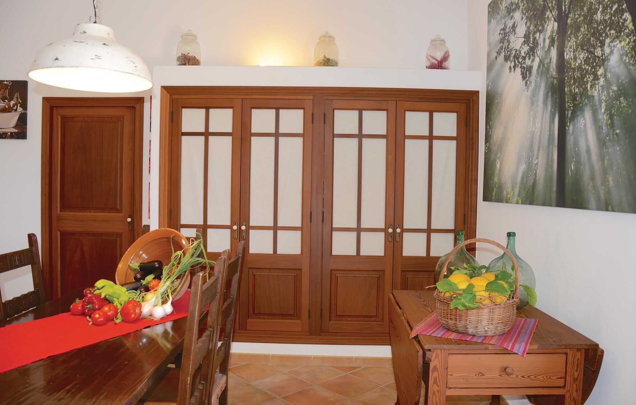A dining area with a wooden table, chairs, a red runner, and a basket of lemons.
