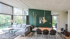 A modern living room with a grey sofa, a dining table with chairs, and a green accent wall. - 3 bedroom cozy home in Roslev (Roslev)