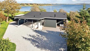 A modern house with a covered patio, a garage, and a view of a lake. - 3 bedroom cozy home in Roslev (Roslev)