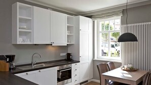 Una cucina moderna con mobili bianchi, forno integrato e zona pranzo con tavolo e sedie.