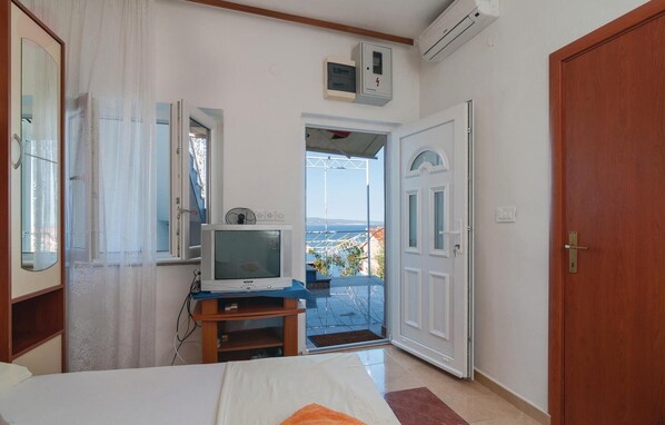Une chambre à coucher comprenant un lit, un téléviseur posé sur un meuble, une armoire et une porte donnant sur un balcon avec vue.