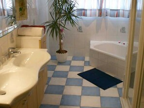 A bathroom with a checkered floor, a sink, a bathtub, and a potted plant. - Apartment 2 - Ferienhof Nußbaumer (Gaisberg)
