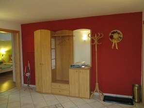 Une pièce comprenant une armoire en bois, un miroir, un porte-manteau et une poubelle.