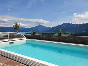 A swimming pool with a mountain view, a palm tree, and a potted plant. - Apartment 2 - Ferienhof Nußbaumer (Gaisberg)