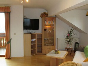 Ein Wohnzimmer mit Fernseher, Holzschrank und Pflanze.