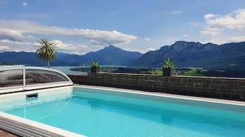 En swimmingpool med udsigt til et bjerg, en palme og en potteplante.