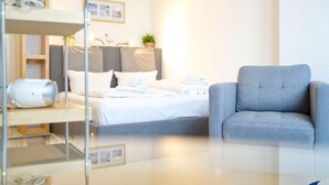 A modern hotel room with a bed, a grey armchair, and a bedside table with a lamp. - Rolandseck I, Apt. 04 - A Little Oasis Near the Beach - RO I 04 (Heringsdorf)