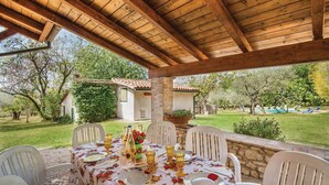 An outdoor patio with a wooden roof, a table set for dining, and a view of a garden and pool. - 4 bedroom nice home in Terni TR (Terni TR)