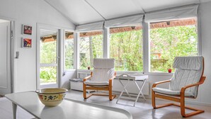A room with two rocking chairs, a small table, and a window with a view of greenery. - 2 bedroom stunning home in Græsted (Græsted)