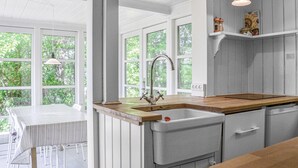 A kitchen with a wooden countertop, a sink with a vintage faucet, and a window overlooking greenery. - 2 bedroom stunning home in Græsted (Græsted)