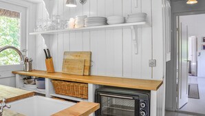 A kitchen with white wooden cabinets, a wooden countertop, a sink, a stove, and shelves with dishes and glasses. - 2 bedroom stunning home in Græsted (Græsted)
