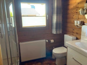 Un baño pequeño con inodoro, radiador, ventana y lavamanos.