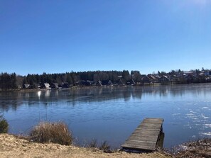 A calm lake with a wooden dock extending into the water, surrounded by houses and trees. - Blockhouse 30. 53 - Waldsee holiday service (Clausthal-Zellerfeld)