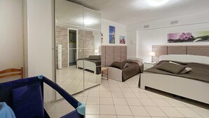 A modern bedroom with a large bed, a smaller sofa, a desk, and a mirror. - Stunning home in Villanuova sul C. BS with outdoor swimming pool (Villanuova sul C. BS)