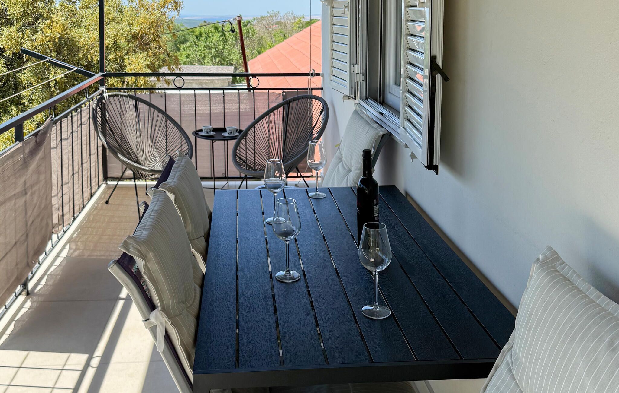 A balcony with a table, two chairs, and a bottle of wine.