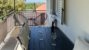 Un balcón con una mesa, dos sillas y una botella de vino.