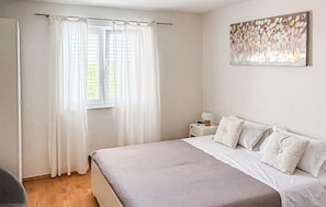 Une chambre à coucher avec un lit, des rideaux, une table de chevet et une œuvre d’art murale.