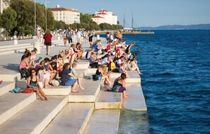 A public waterfront area with steps leading to the water, where people are sitting and relaxing.
