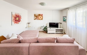 Un salon moderne avec un canapé, un téléviseur et des œuvres d’art accrochées aux murs.