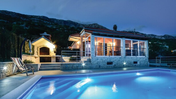 A poolside villa with a stone exterior, a glass-enclosed patio, and a swimming pool.
