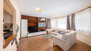 A modern living room with a sofa, a glass coffee table, and a flat-screen TV.