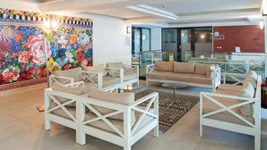 Eine moderne Lobby mit weißen Möbeln, einem farbenfrohen Blumenwandbild und einem Empfangstresen.