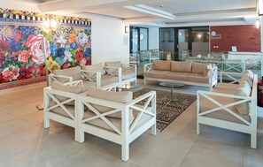 Een moderne lobby met witte meubels, een kleurrijke bloemenmuur en een receptiebalie.