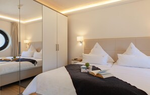 Een hotelkamer met een bed, nachtkastje, spiegel en raam met gordijnen.