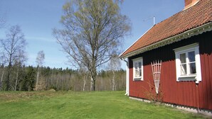 Et rødt træhus med tegltag, hvide vinduer og skorsten.