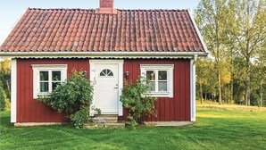 Et rødt træhus med tagsten, to vinduer og en hvid dør.