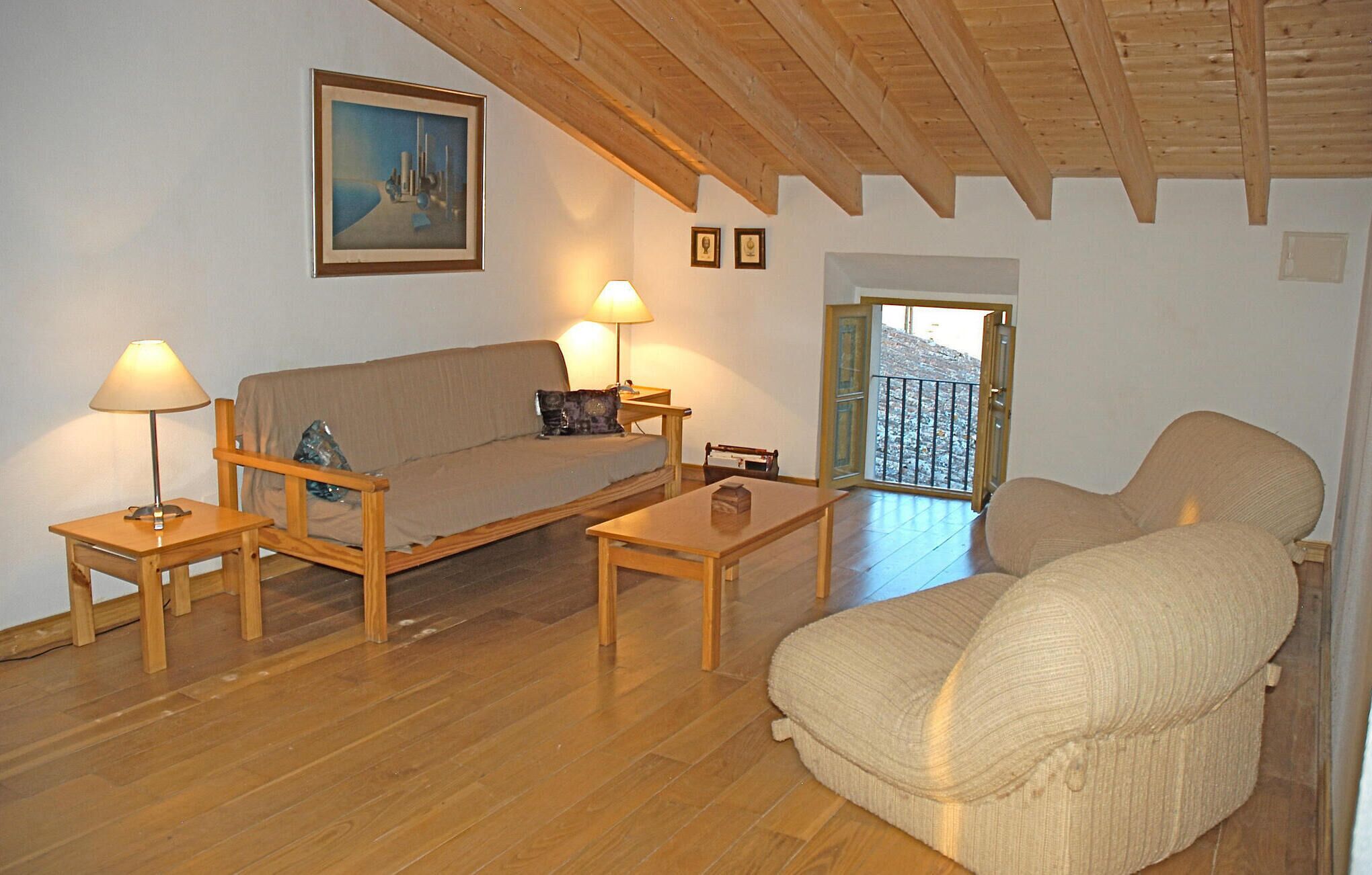 A cozy living room with a wooden ceiling, a sofa, two armchairs, a coffee table, and a painting on the wall.
