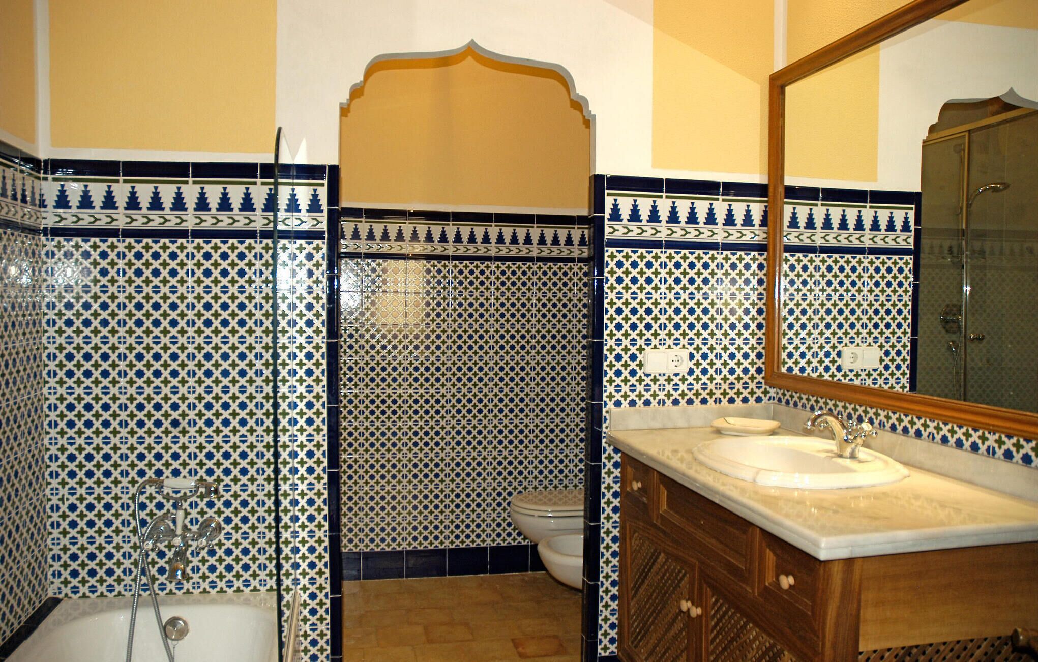A bathroom with patterned tiles, a bathtub, a sink, and a mirror.