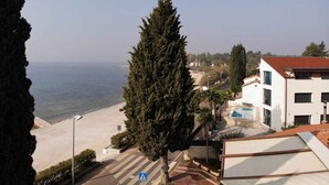 Une vue sur la côte, avec une plage, un grand arbre et un bâtiment doté d’une piscine.