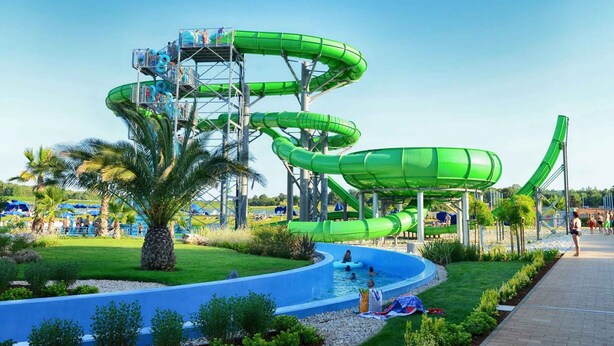 Un parc aquatique doté de plusieurs toboggans aquatiques verts et d’un espace piscine.
