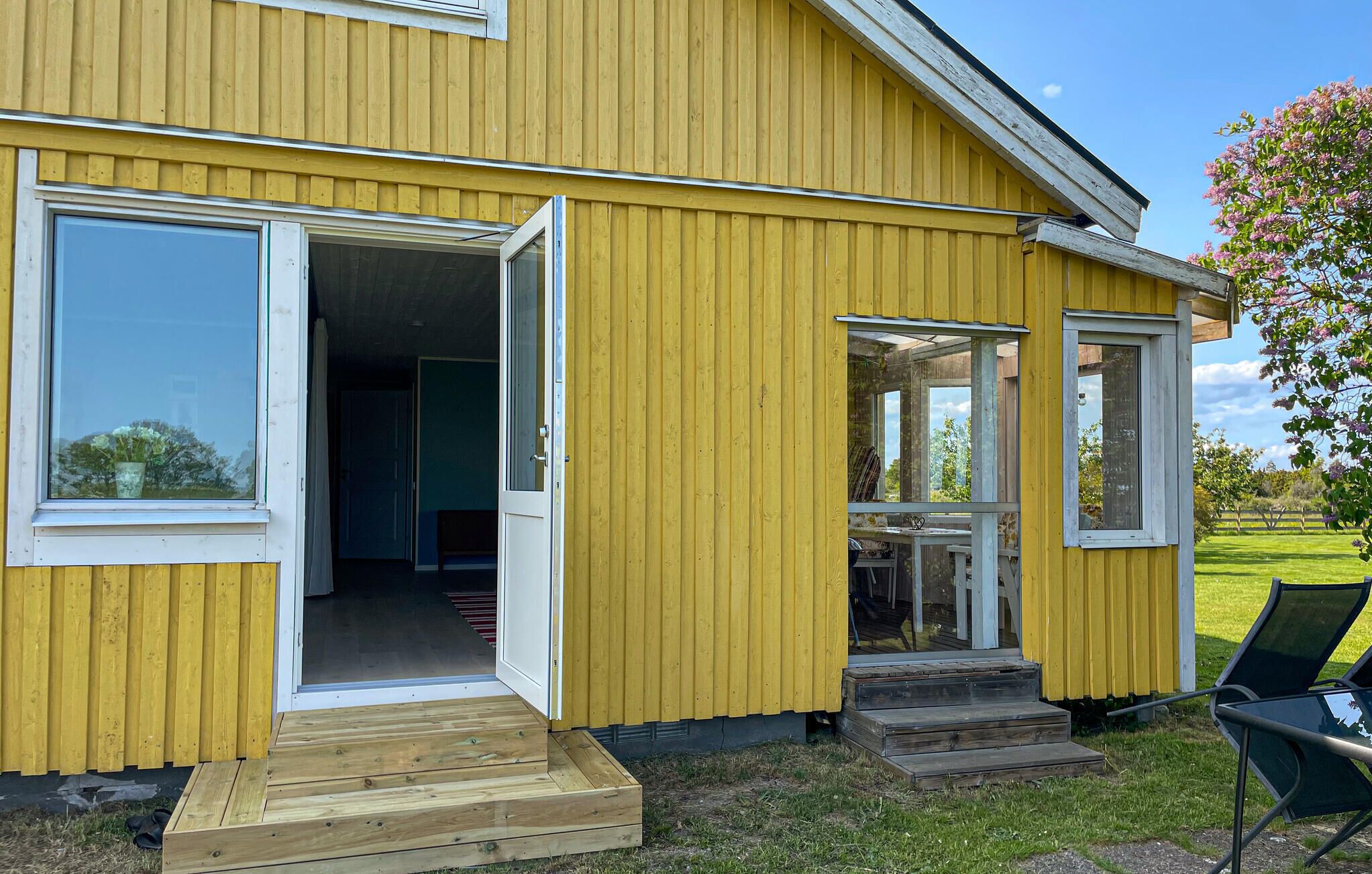 Un edificio amarillo con dos puertas abiertas que dan a una habitación con una mesa y sillas.
