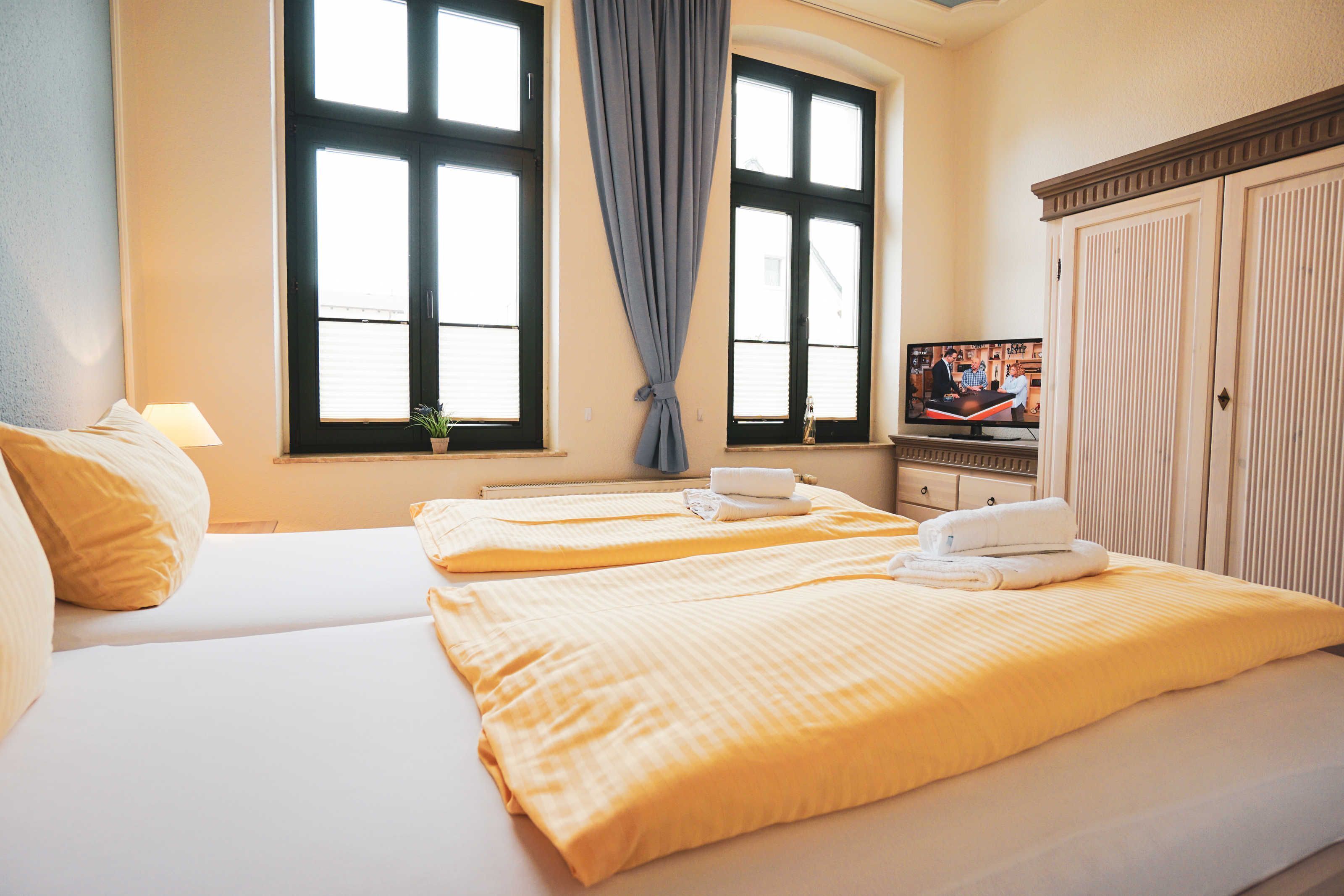 Ein Hotelzimmer mit zwei Betten, einem Fernseher und einem Kleiderschrank.