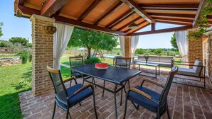 An outdoor patio with a brick floor, metal-framed table and chairs, a cushioned sofa, and a hanging plant. - Lovely home in Cukrici with WiFi (Cukrici)