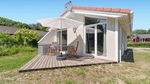 Une maison moderne dotée d’une terrasse en bois, d’une grande porte-fenêtre coulissante et d’une antenne parabolique.