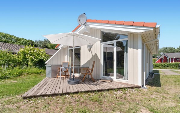 Una casa moderna con terraza de madera, un amplio ventanal corredero y una antena parabólica.
