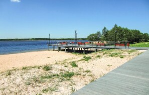 Ein Strand mit einer Holzpromenade und roten Bänken.