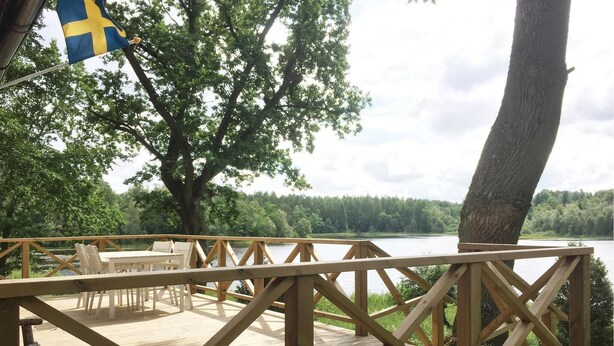 Eine Holzterrasse mit Sitzgelegenheiten und Blick auf einen See.