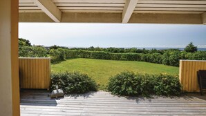 A wooden deck leading to a grassy yard with a view of the sea. - Lovely home in Kalundborg with kitchen (Kalundborg)