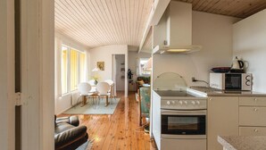 A compact kitchen with a stove, microwave, and a dining area with chairs and a table. - Lovely home in Kalundborg with kitchen (Kalundborg)
